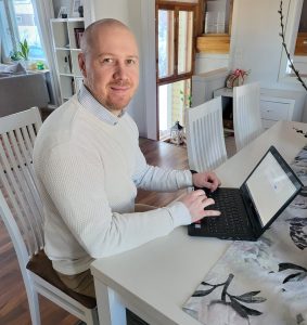 Olli Malkavaara istuu pöydän ääressä tietokoneella etätyöpäivänään.